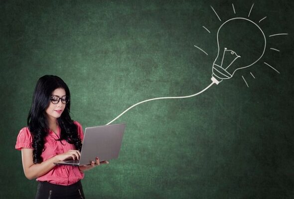 [freepicdownloader.com]-woman-uses-laptop-with-light-bulb-classroom-normal