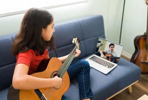 hispanic-girl-with-music-skills-listening-instructions-her-guitar-teacher-video-call-laptop-while-sitting-sofa-home_662251-1413